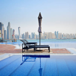 Rooftop pool with lounge chairs offering a panoramic view of Dubai's skyline, highlighting modern utility infrastructure.