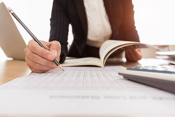 Person reviewing financial documents with a calculator at a desk, representing mortgage application process.