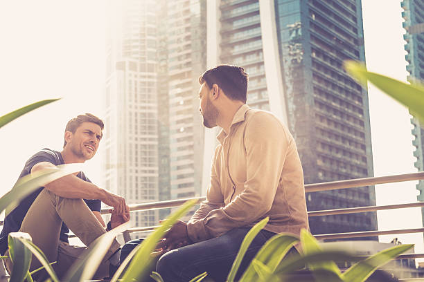 Two men converse outdoors with Dubai skyscrapers in the background during a utility connection tour.