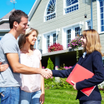 A couple is shaking hands with a real estate agent in front of a large house.