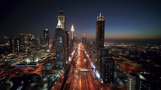 Aerial night view of a vibrant, illuminated cityscape, showcasing the potential surroundings of Damac Hills 2.